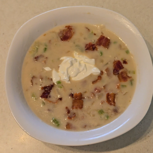 image of a bowl of sherry calm chowder with bacon bits and a dollop of sour cream