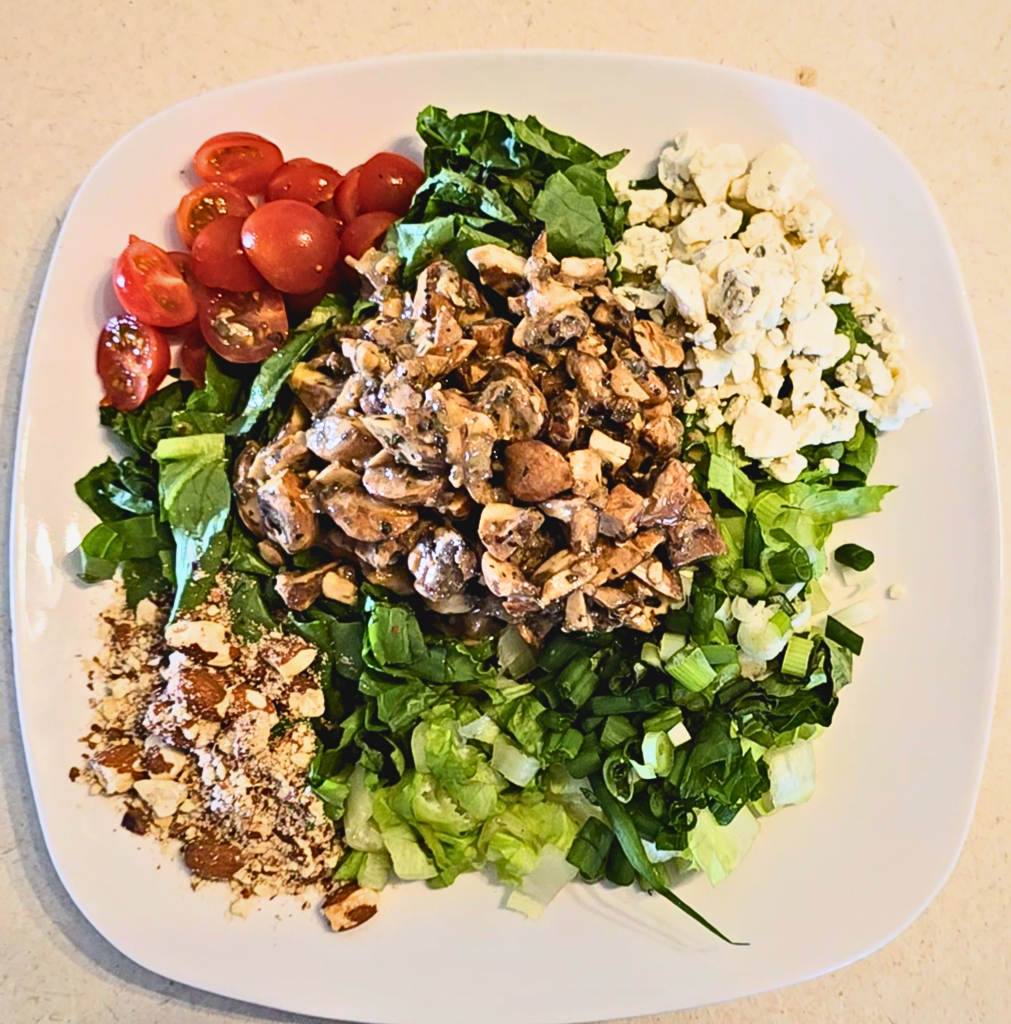Lettuce greens, cherry tomatoes, blue cheese crumbles, green onions and walnuts (in this case almonds) come together with marinated mushrooms in this divine salad.